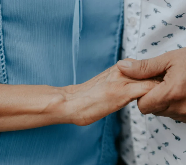 A close view of two people standing side by side, one person's hand closed around the other's