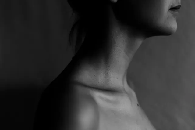 Black-and-white close-up of a person's neck and shoulder in profile
